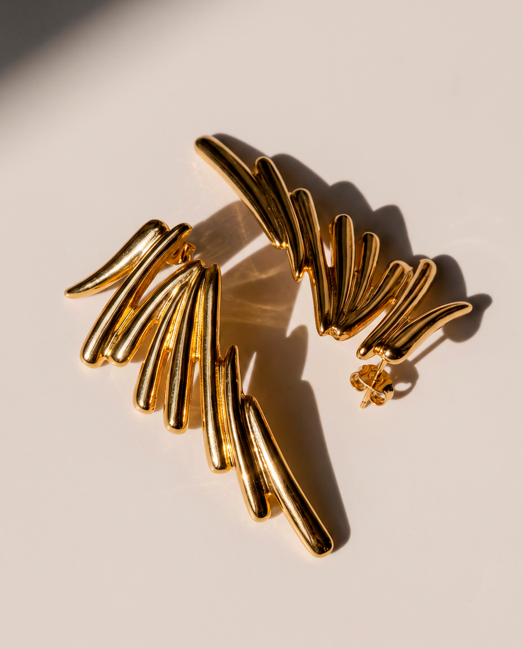Gold wing statement earrings with sculptural graduated ribs and 18k gold-plated finish, Selva Line by Azulique.