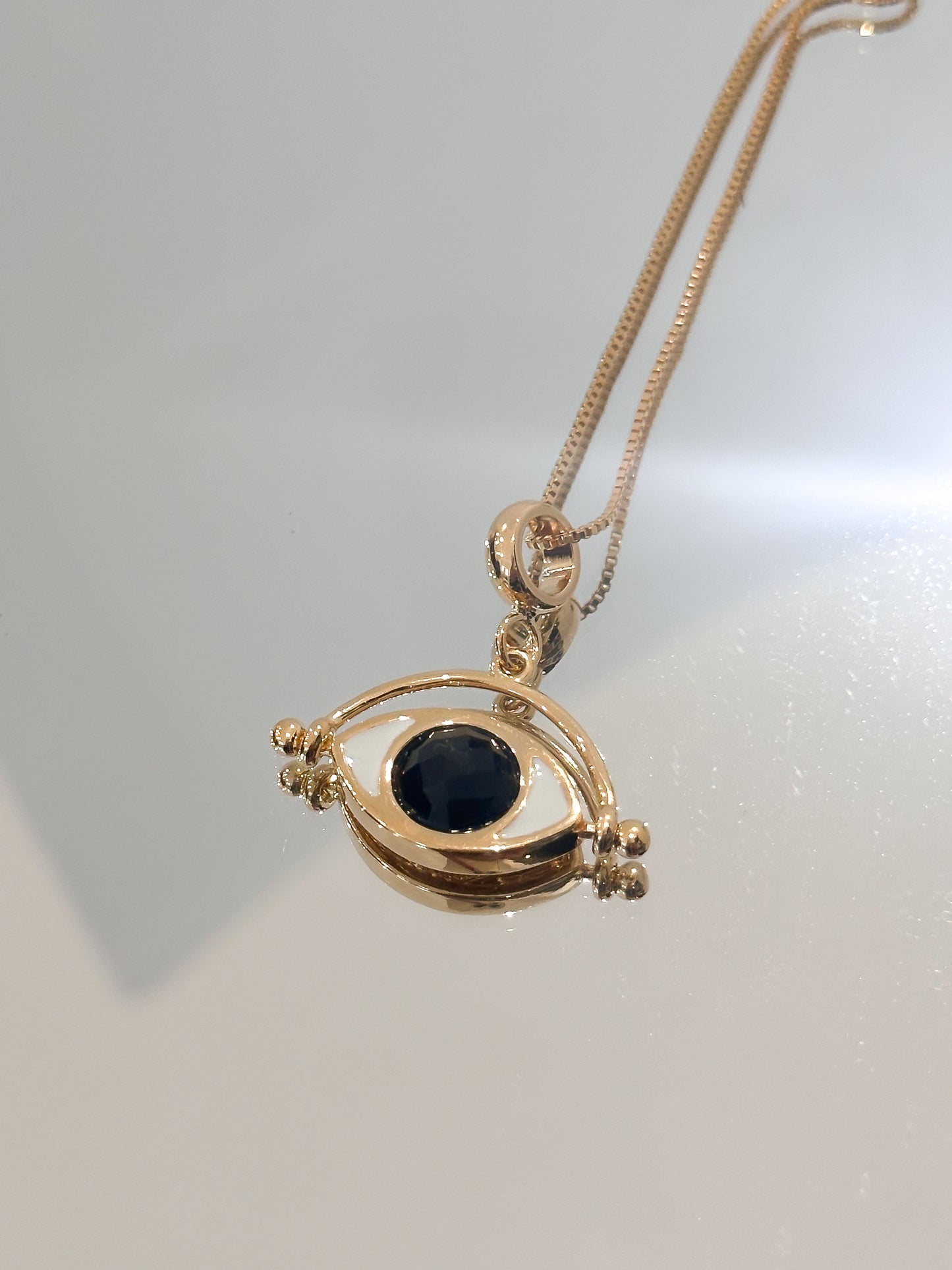 Gold necklace with a black Obsidian gemstone pendant on a light gray background