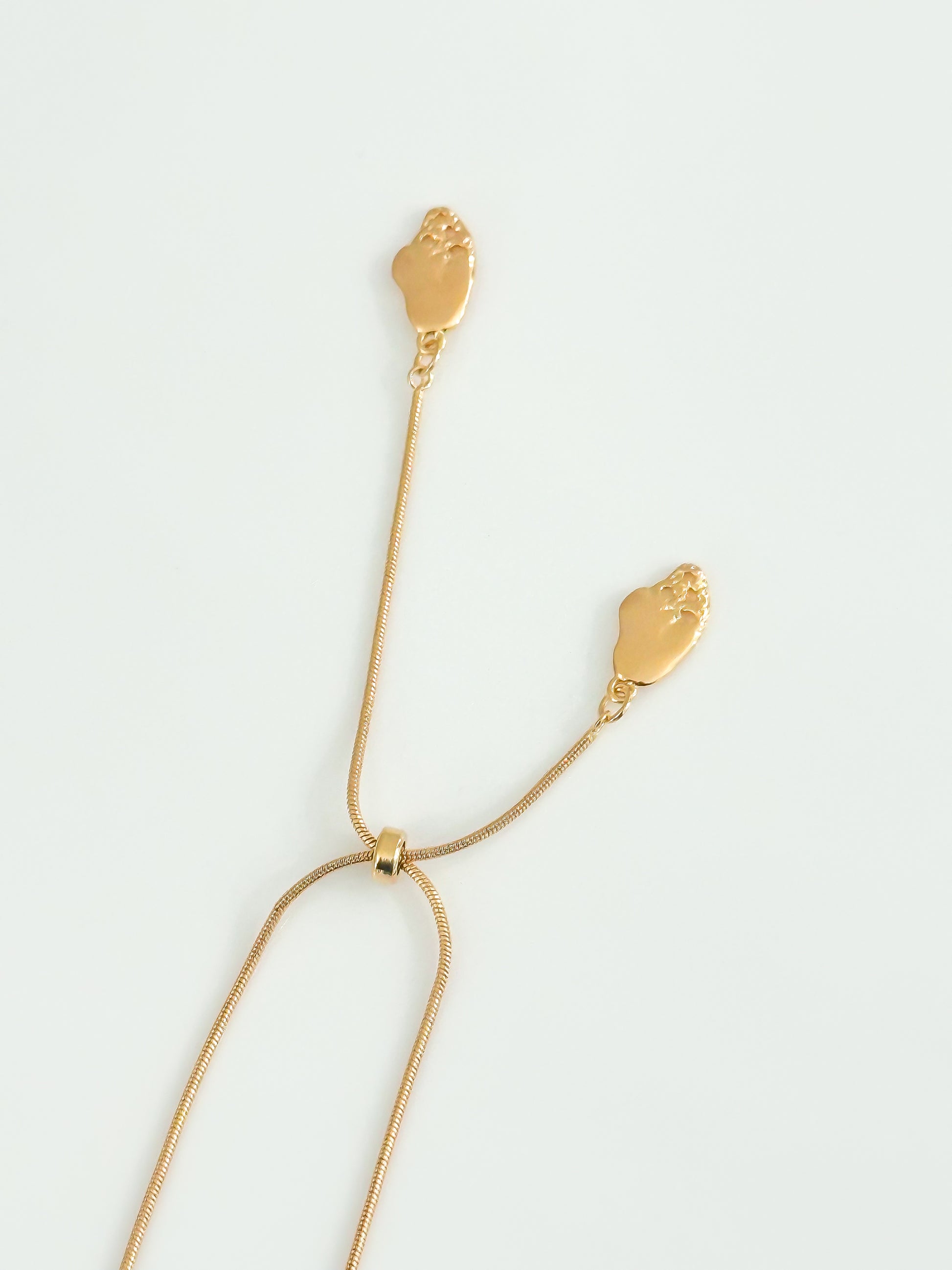 Gold necklace with leaf-like pendants on a light gray background