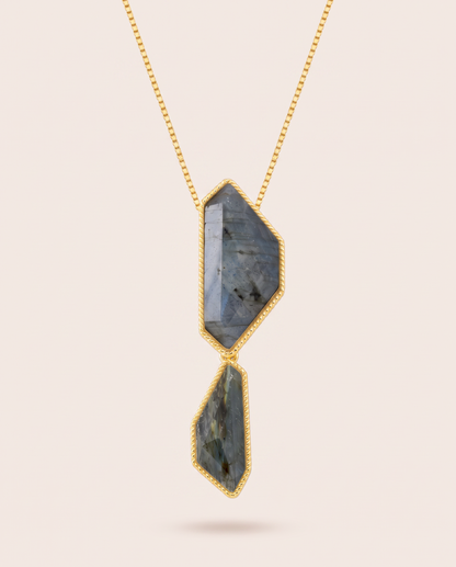 Vertical front view of the Nocturne necklace featuring two faceted, geometric blue labradorite stones in rope-detailed gold-plated bezels suspended from a fine gold box chain.