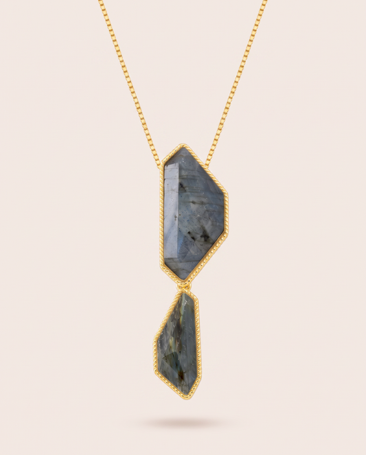 Vertical front view of the Nocturne necklace featuring two faceted, geometric blue labradorite stones in rope-detailed gold-plated bezels suspended from a fine gold box chain.