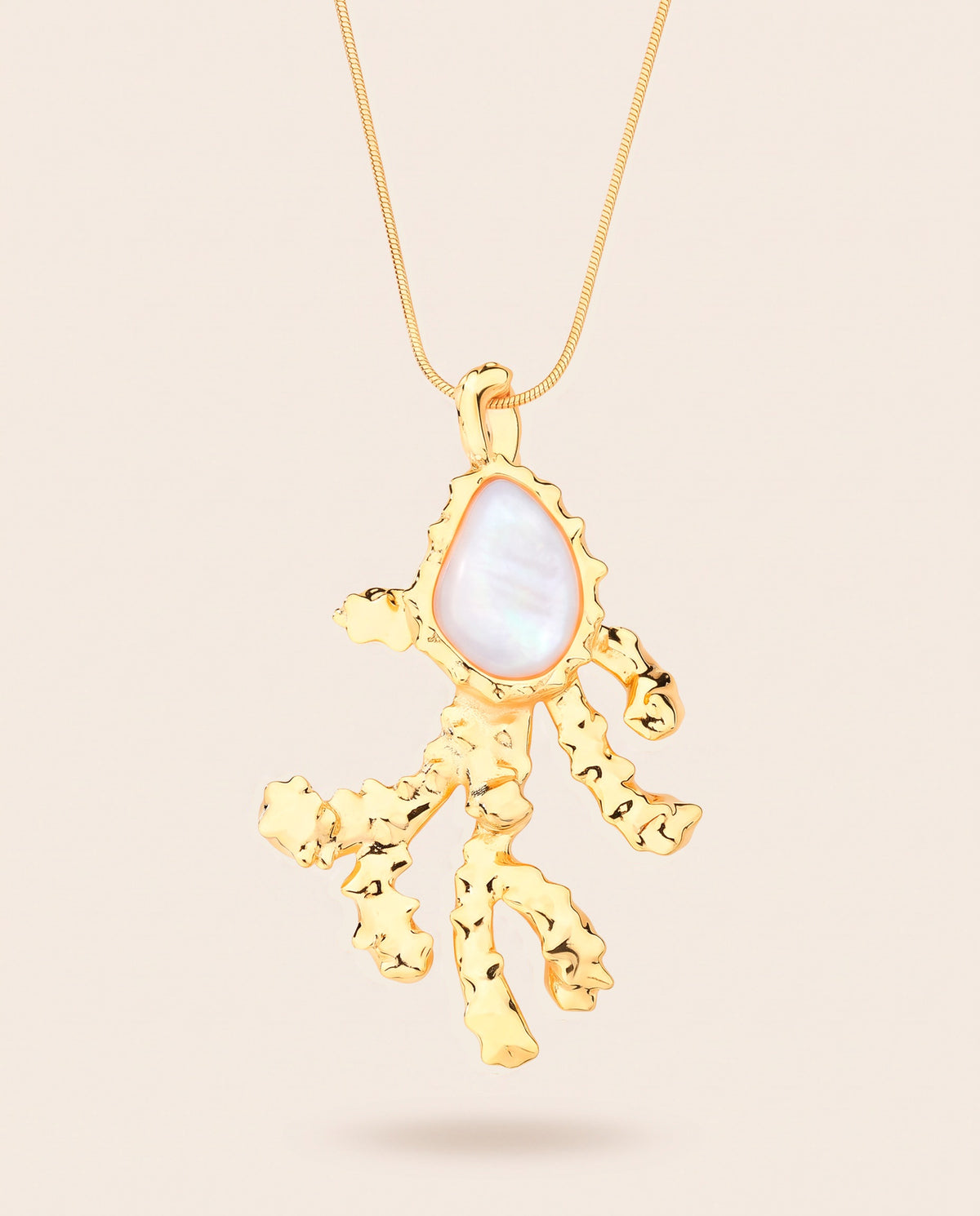Long gold-plated Coralia coral branch pendant necklace with pear-shaped mother of pearl worn over a square neckline top