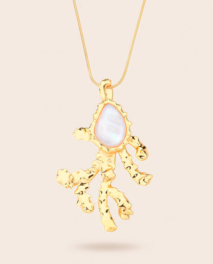 Long gold-plated Coralia coral branch pendant necklace with pear-shaped mother of pearl worn over a square neckline top