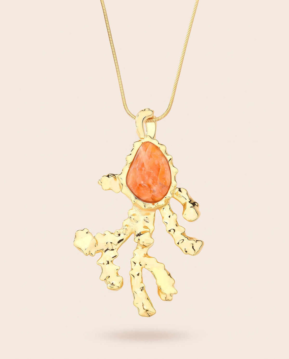 Long gold-plated Coralia coral branch pendant necklace with pear-shaped orange calcite worn over a square neckline top