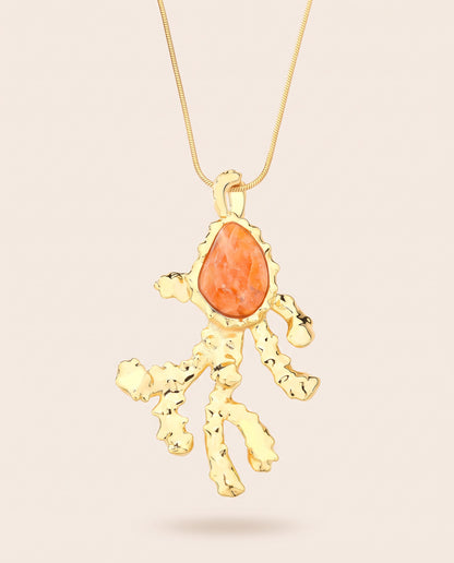 Long gold-plated Coralia coral branch pendant necklace with pear-shaped orange calcite worn over a square neckline top