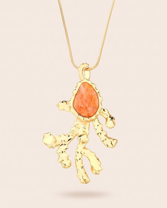 Long gold-plated Coralia coral branch pendant necklace with pear-shaped orange calcite worn over a square neckline top