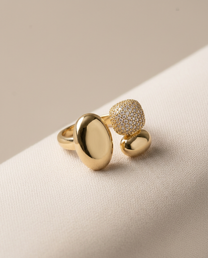 Crimson gold statement ring with two polished oval forms of different sizes and a rounded pavé cluster.