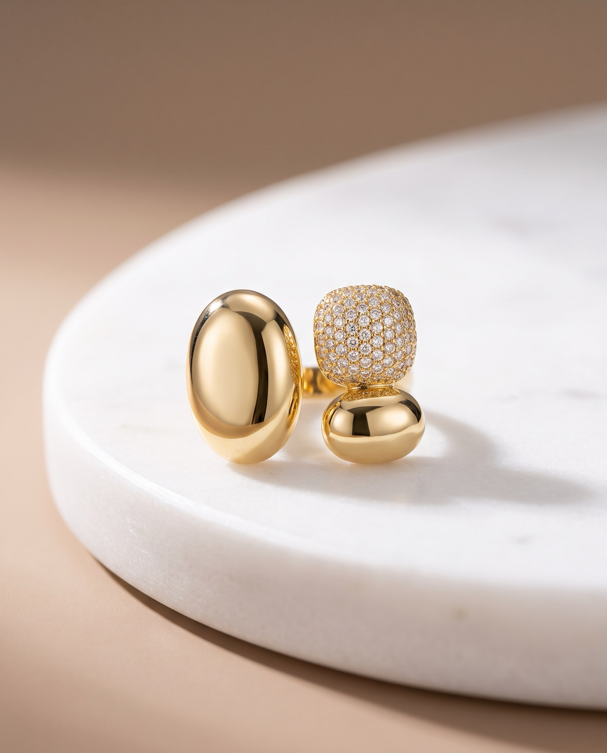 Crimson gold statement ring with two polished oval forms of different sizes and a rounded pavé cluster.