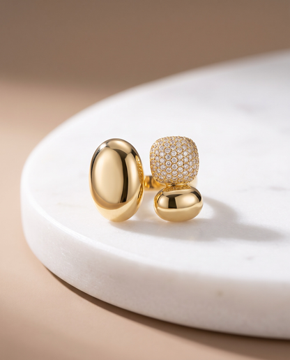Crimson gold statement ring with two polished oval forms of different sizes and a rounded pavé cluster.