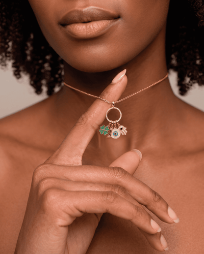 woman wearing Gold plated Sorte lucky charm necklace with cubic zirconia figa, four leaf clover, evil eye and hamsa charms