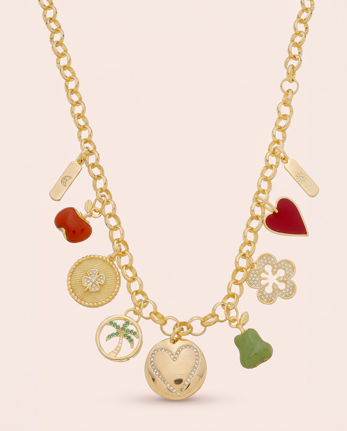Gold charm necklace with nine charms on a rolo chain, including a red resin apple, a green resin pear, a red heart and a crystal pavé heart disc.