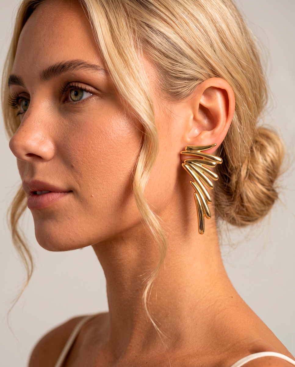 Woman wearing Gold wing statement earrings with sculptural graduated forms and 18k gold-plated finish. by Azulique