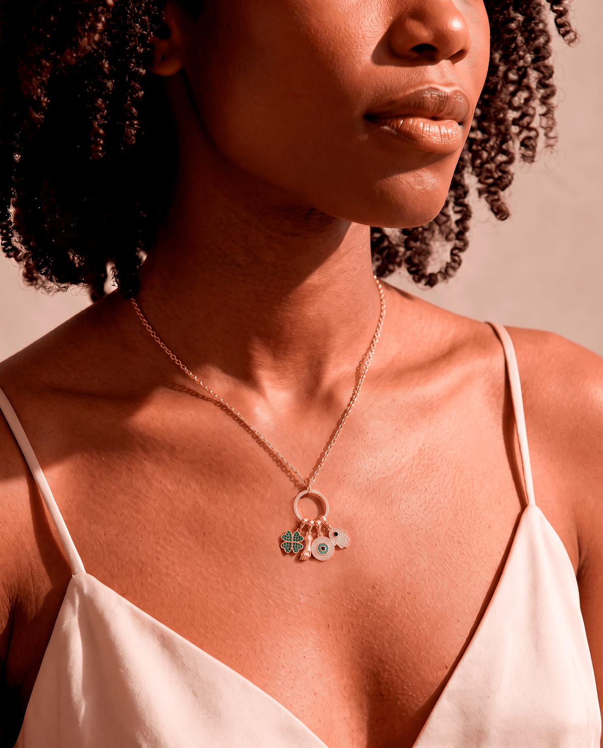 woman wearing Gold plated Sorte lucky charm necklace with cubic zirconia figa, four leaf clover, evil eye and hamsa charms